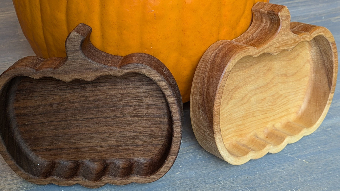 Wooden pumpkin candy dishes on a table with a pumpkin in the background